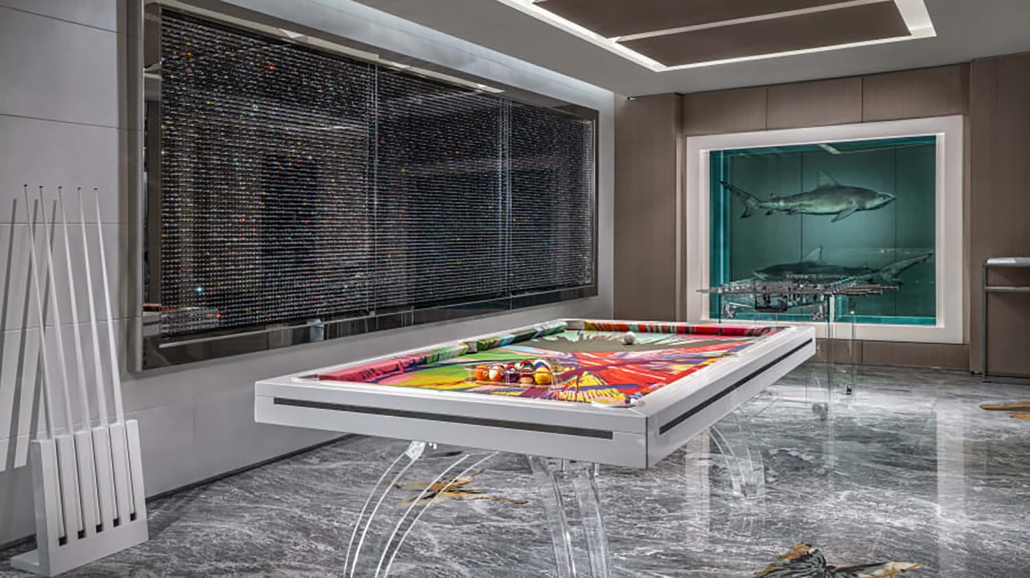Modern game room with a colorful pool table, wall art, and a display case featuring a preserved shark, on a marble floor.