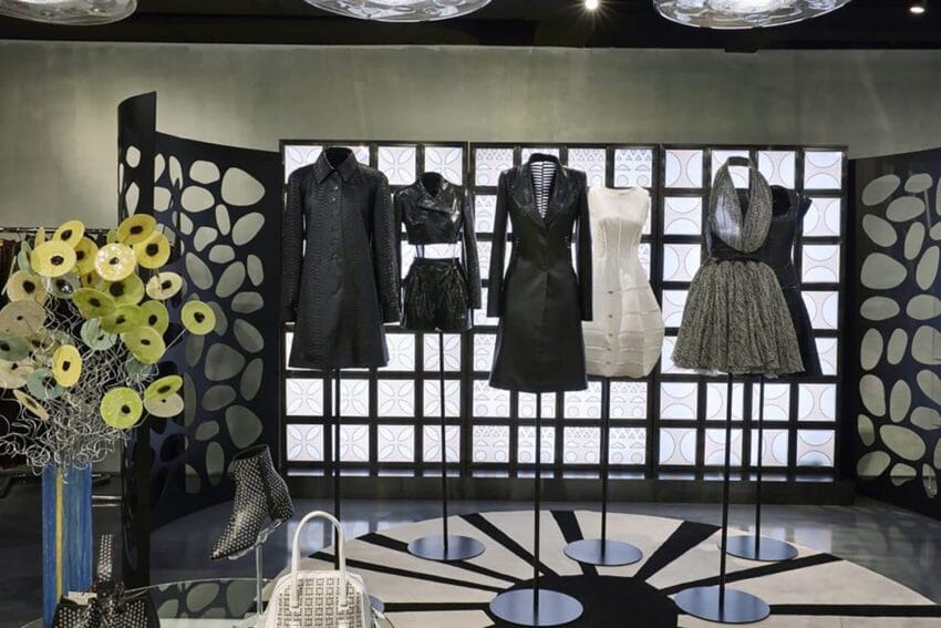Fashion display with stylish black and white dresses on mannequins, decorative backdrop, and modern lighting.