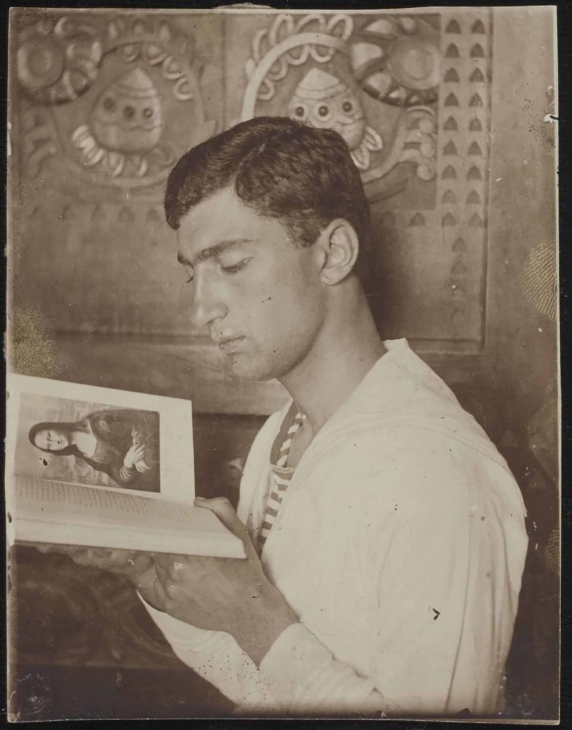 Young man reading a book in sepia-toned photograph with a decorative background.