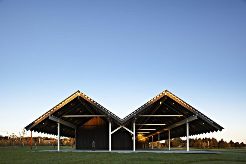 Modern pavilion with geometric roof design under a clear blue sky