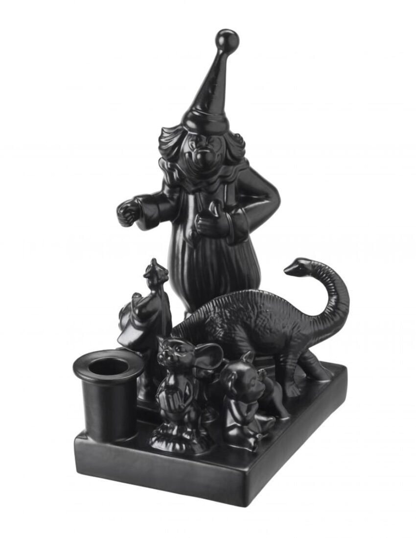 Black clown figurine with animals on a rectangular base, featuring a dinosaur and other small creatures.