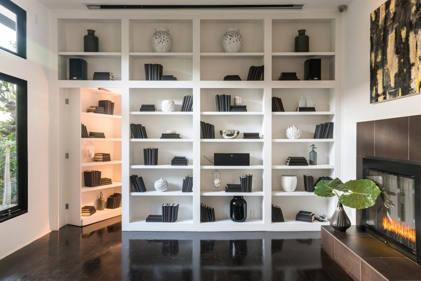Modern living room with white built-in bookshelves, black and white decor, dark wood floor, and a fireplace.