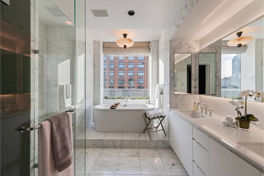 Luxurious marble bathroom with a soaking tub, large windows, and modern fixtures.