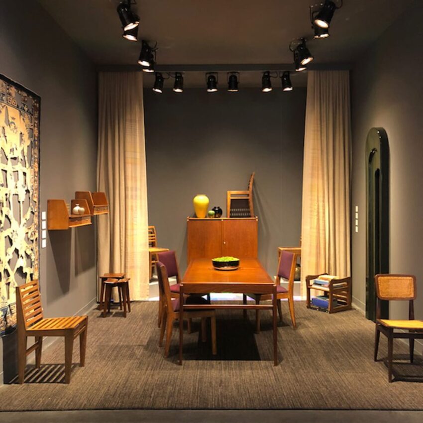 Mid-century modern dining room with wooden table, chairs, and decor against dark walls and soft lighting.