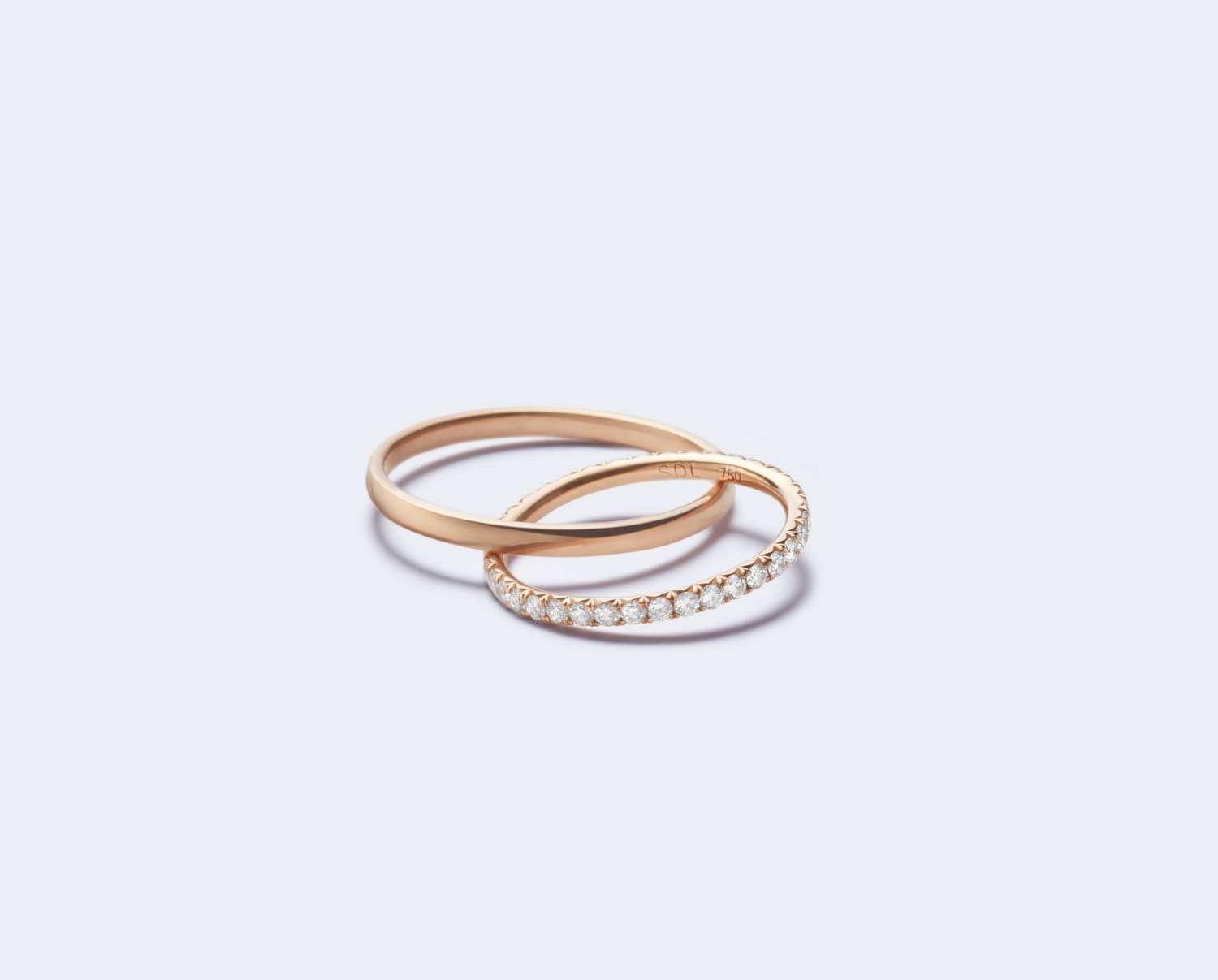Two elegant rose gold rings, one with diamonds and one plain, on a light background.