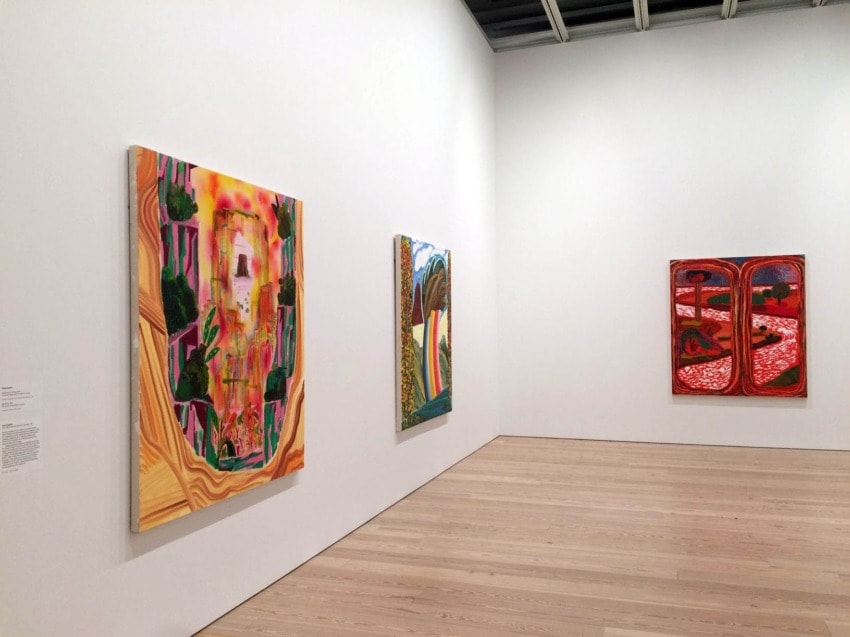 Art gallery with colorful abstract paintings displayed on white walls.