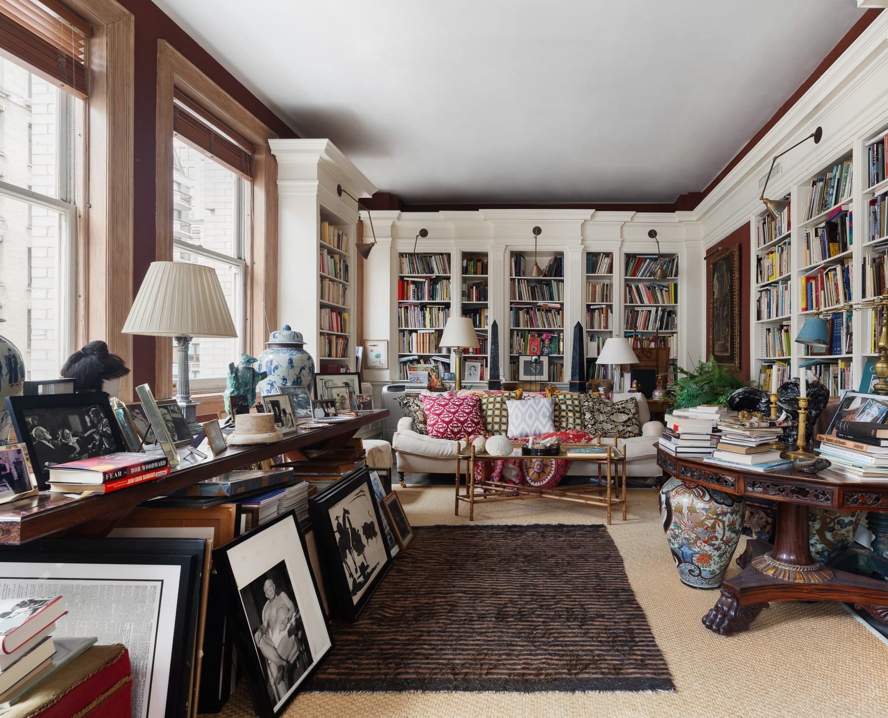 Cozy home library with bookshelves, framed photos, plush seating, and large windows for natural light.