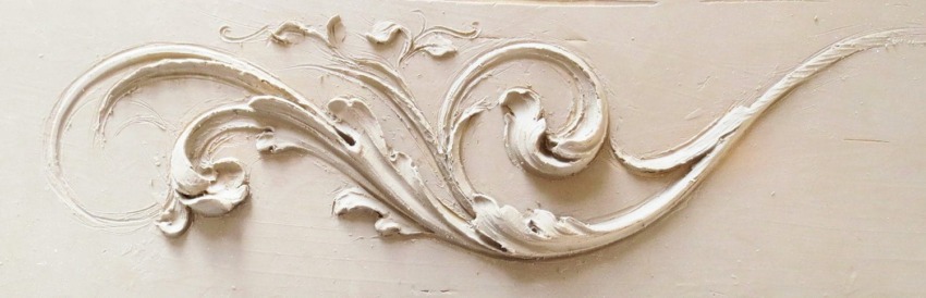 Ornate plaster wall decoration with elegant swirling floral design.