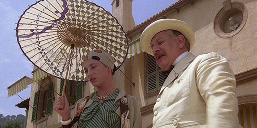 Two people in vintage attire, with one holding a parasol, stand in front of an elegant building with arched windows.