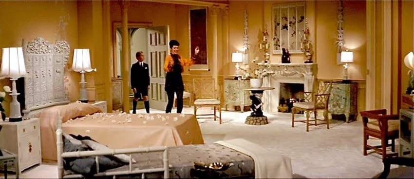 Luxurious vintage room with elegant furnishings, two people conversing, ornate fireplace, and soft lighting ambiance.