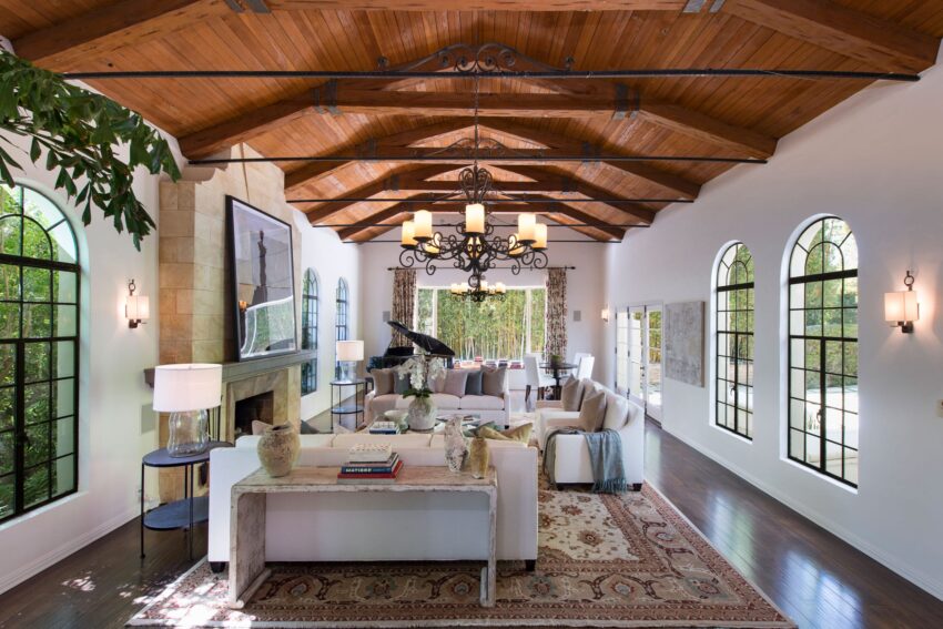 Spacious living room with vaulted wooden ceilings, arched windows, elegant chandelier, and modern decor.