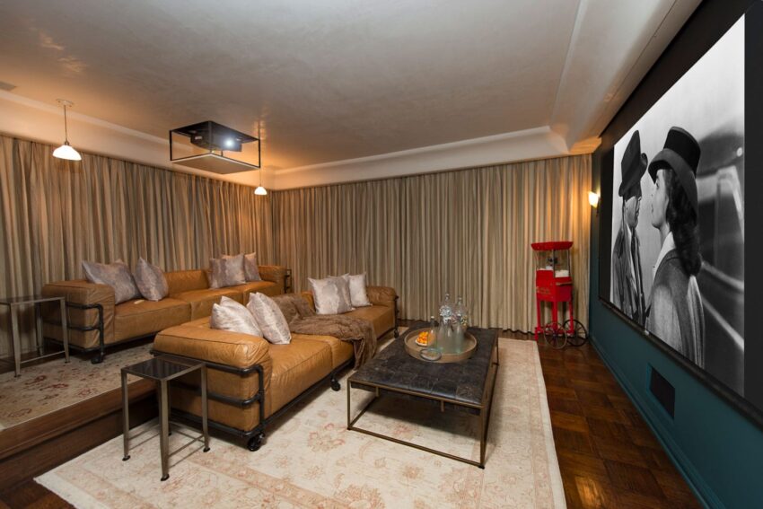 Home theater with leather sofas, a large projector screen displaying a classic movie, and a red popcorn machine.
