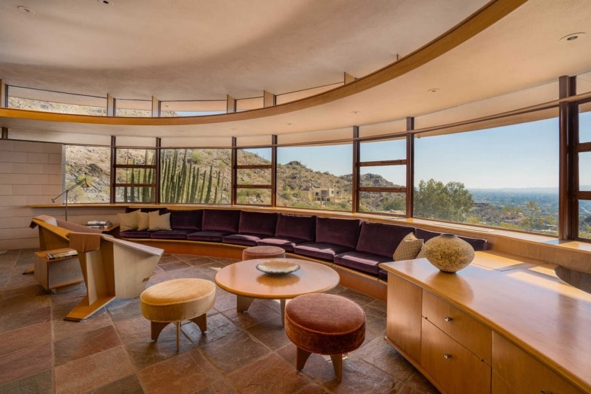 Spacious living room with curved sofa, large windows, and mountain view in a modern architectural home.