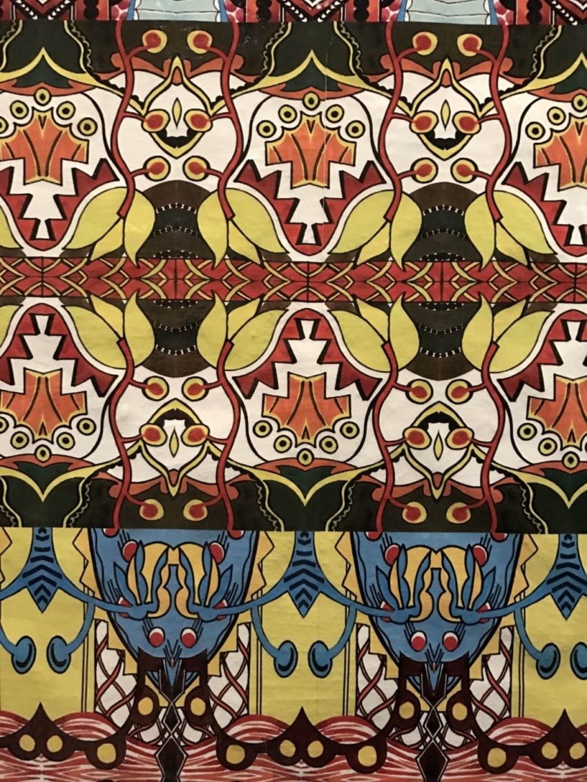 Colorful, symmetrical abstract pattern with intricate geometric and organic shapes in red, yellow, blue, and black.