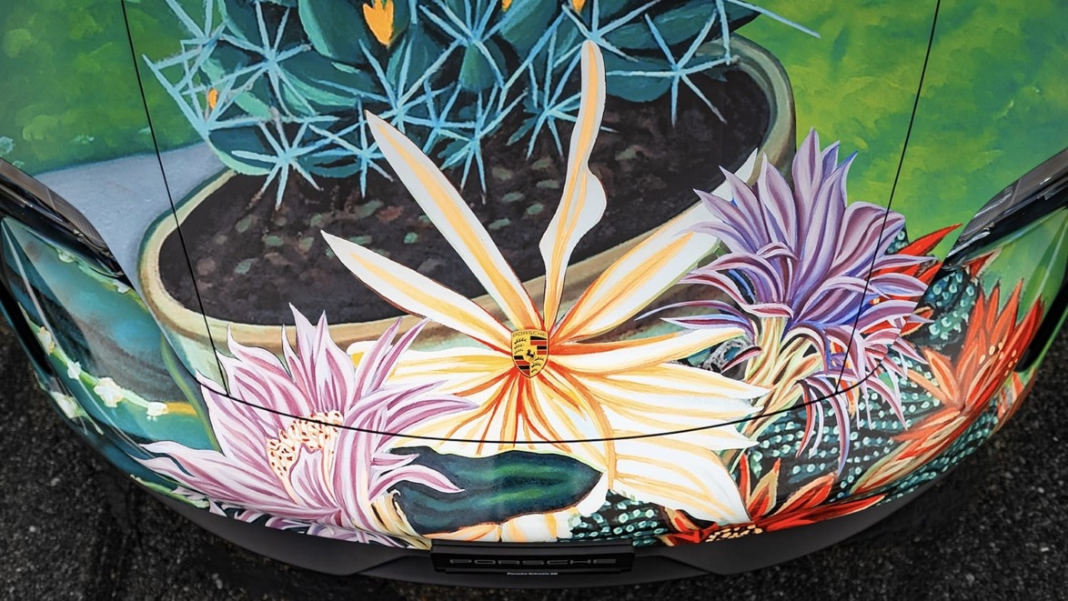 Car hood with colorful floral and cactus artwork, featuring vibrant hues of orange, purple, and green.