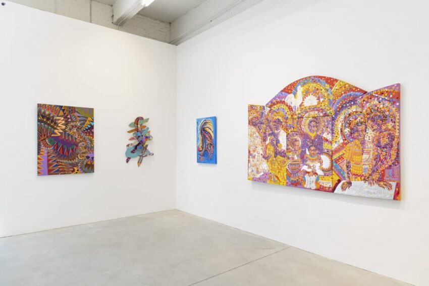 Art gallery with colorful abstract and figurative paintings displayed on white walls.