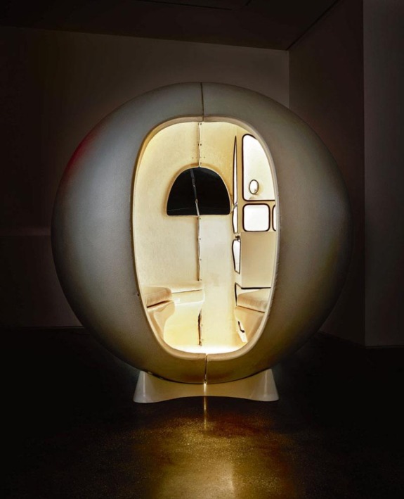 Futuristic spherical pod with a glowing interior and minimalist design in a dimly lit room.