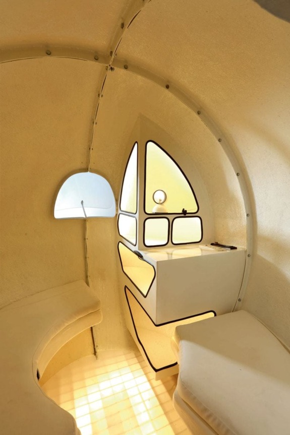 Futuristic white interior with curved walls, minimalistic seating, and a geometric window creating a unique and modern space.