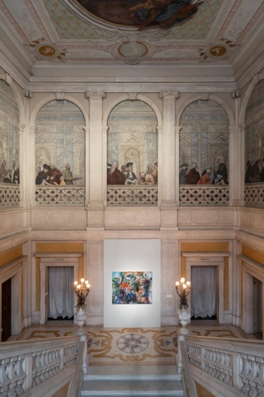 Elegant interior with ornate frescoed walls, grand staircase, and vibrant modern painting displayed on the central wall.