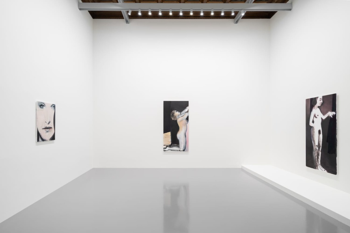 Gallery space with three abstract paintings on white walls, each art piece depicting a human form in different styles.