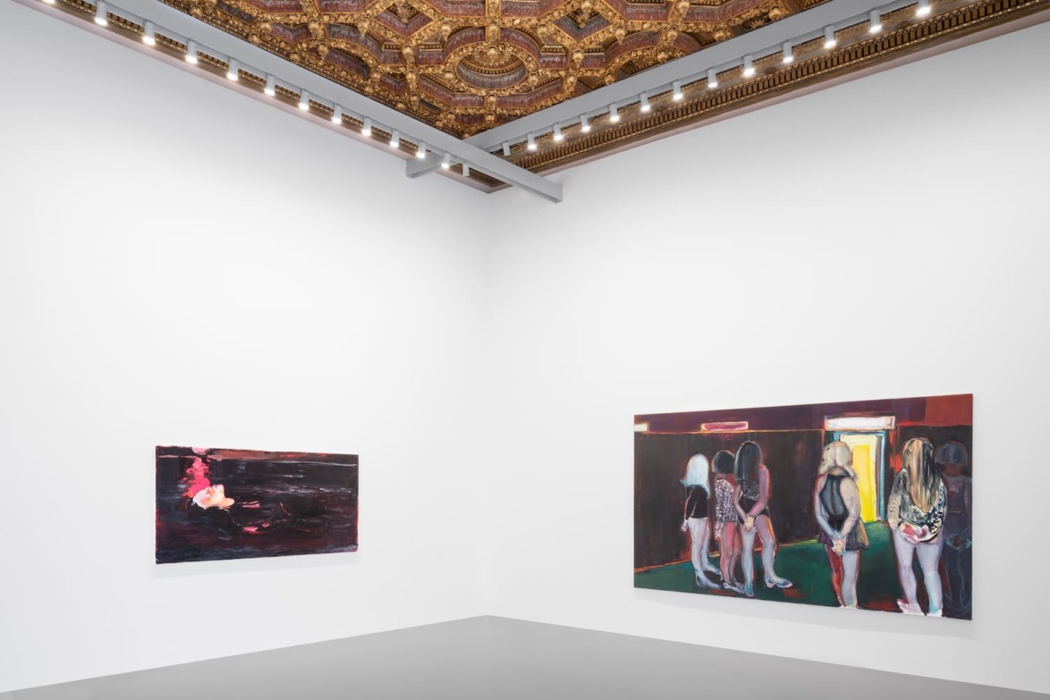 Art gallery interior with modern paintings on white walls and an ornate ceiling.