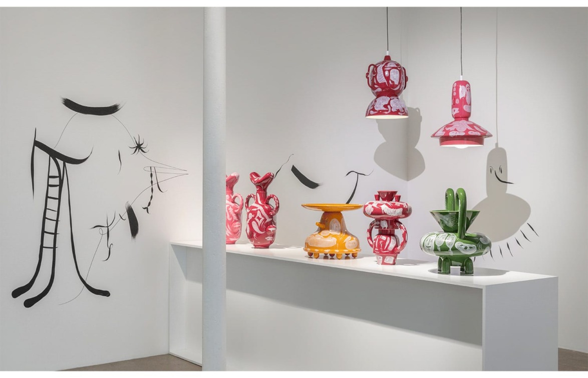 Exhibition of colorful abstract ceramic sculptures and hanging lamps displayed in a modern art gallery setting.