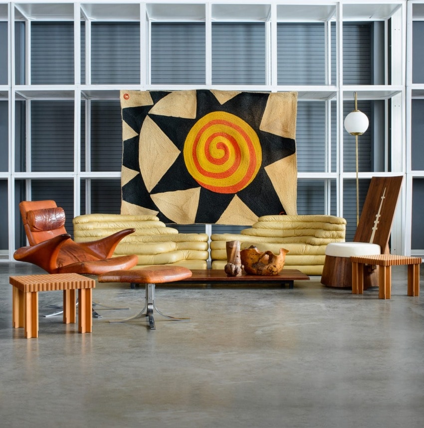 Modern living room with abstract spiral artwork, leather chair, wooden table, and geometric shelving.