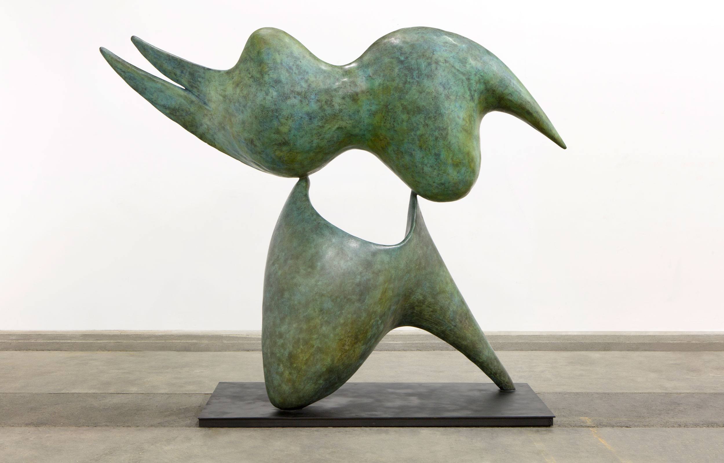 Abstract green sculpture with flowing forms and dynamic shapes on a black base, displayed in a gallery setting.