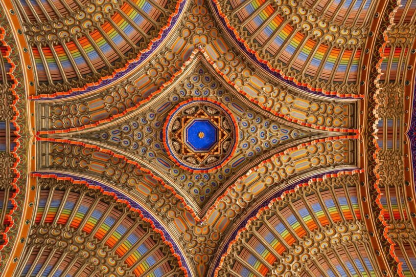 Ornate, colorful ceiling with intricate patterns and a central blue star design in a symmetrical arrangement.