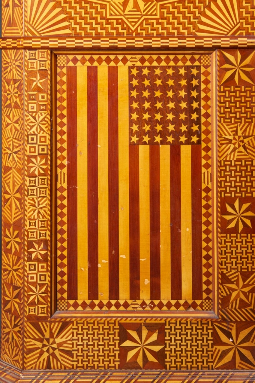 Colorful geometric artwork of an American flag with mosaic border, made from natural wood tones and intricate patterns.