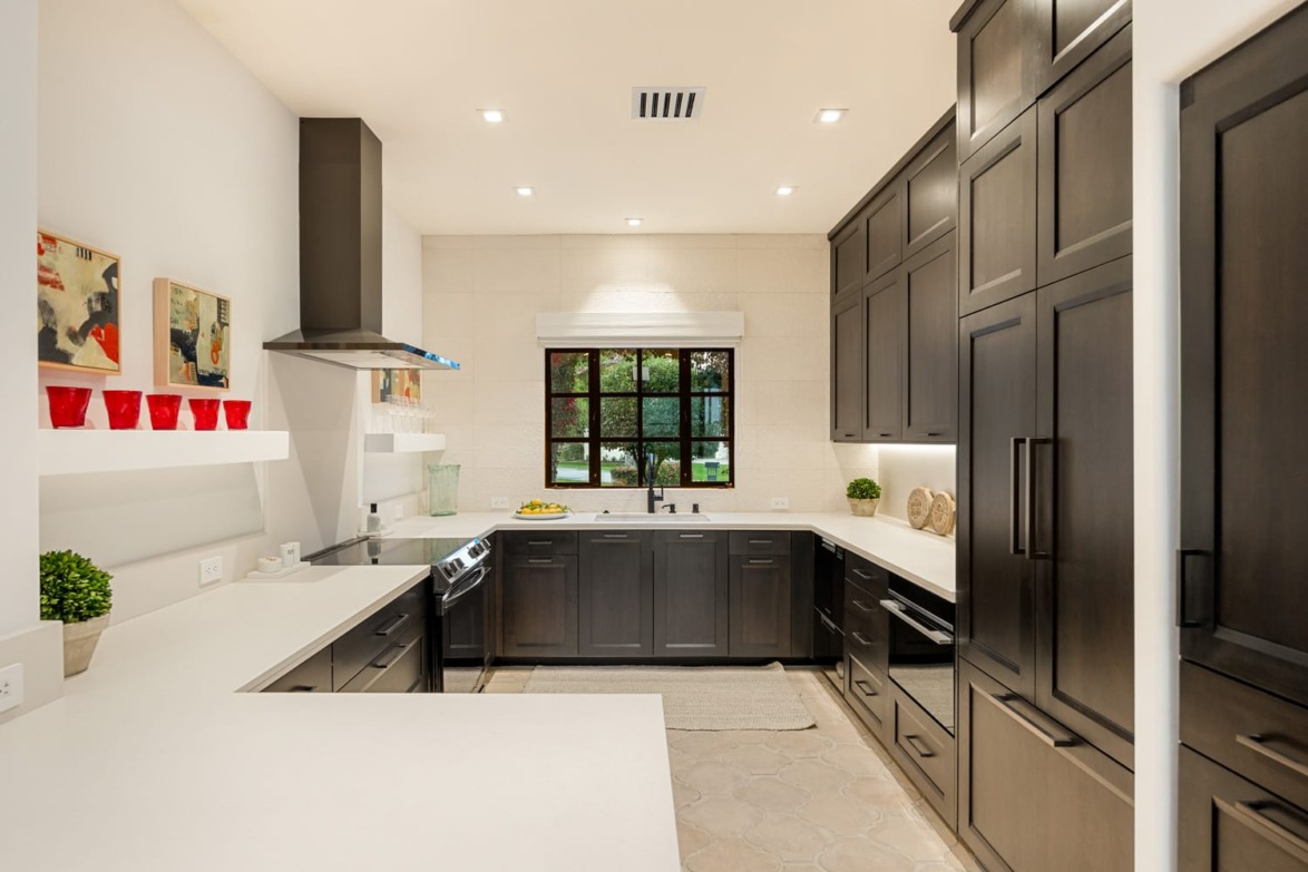 Modern kitchen with dark cabinets, light countertops, stainless steel appliances, and wall art accents.