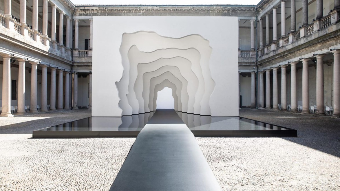 Contemporary art installation with layered arches in a rectangular courtyard, featuring classical architecture with columns.