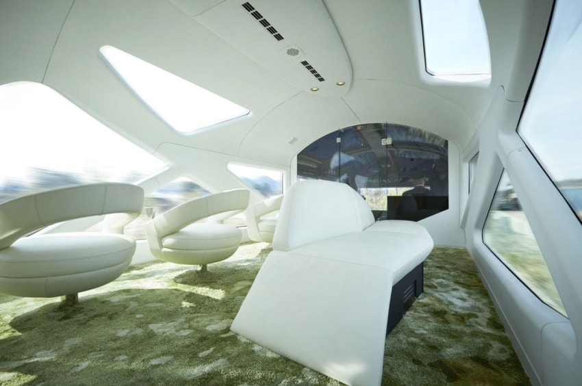 Luxury train interior with white, modern seats, large windows, and skylights providing a spacious and bright atmosphere.