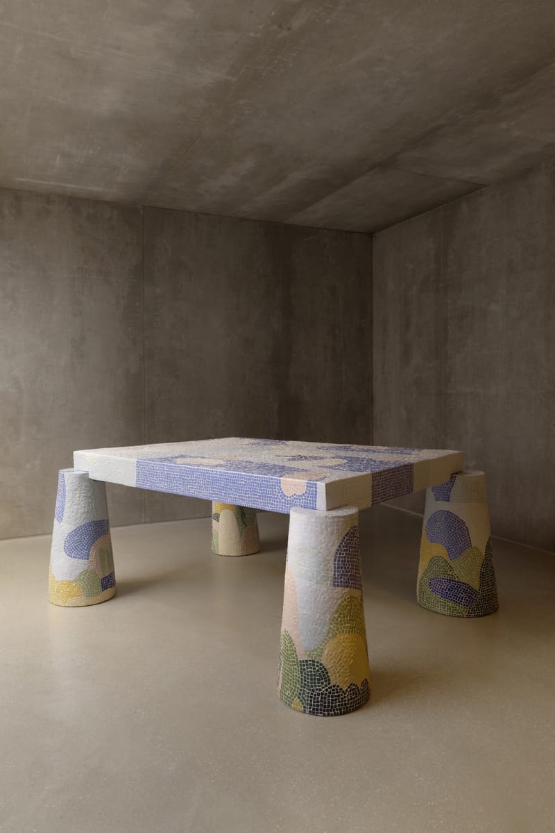 Modern table with colorful mosaic legs in a minimalist concrete room