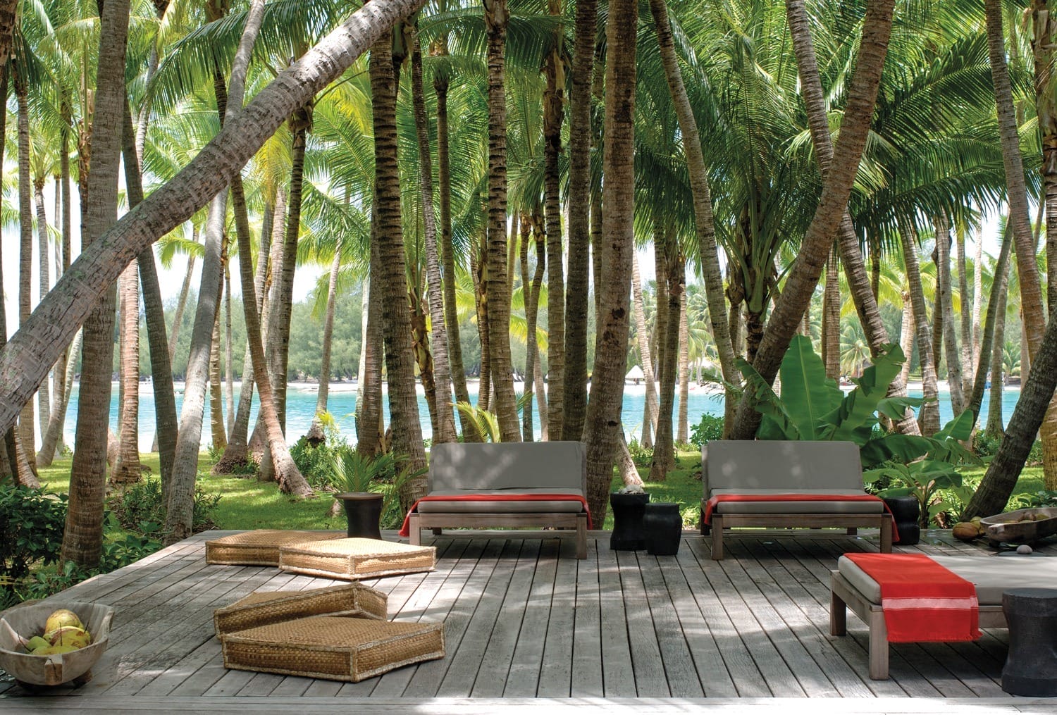 Tropical paradise with palm trees, wooden deck, lounge chairs, and ocean view in a serene, sunny setting.