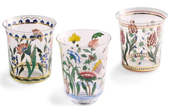 Three intricately decorated glass tumblers with floral patterns in blue, yellow, red, and green hues displayed against a white background.
