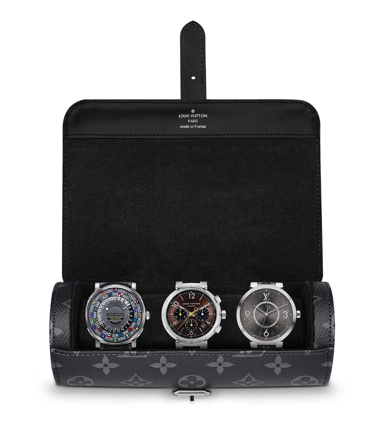 Three luxury watches displayed in an open leather case with a monogram pattern background.