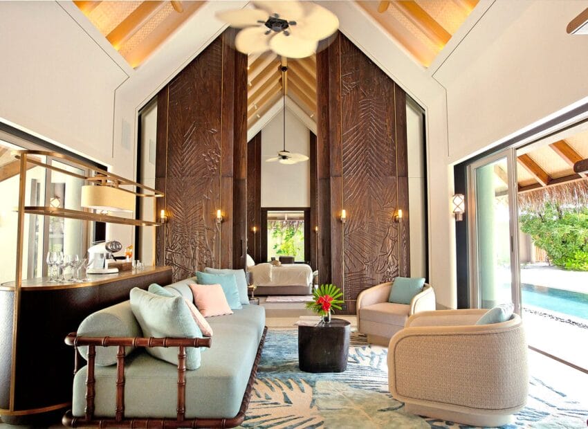 Luxurious tropical living room with high ceiling, elegant furniture, large windows, and access to a pool area.