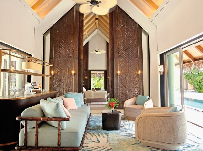 Elegant living room with modern furniture, high wooden ceilings, large windows, and a view of the pool outside.