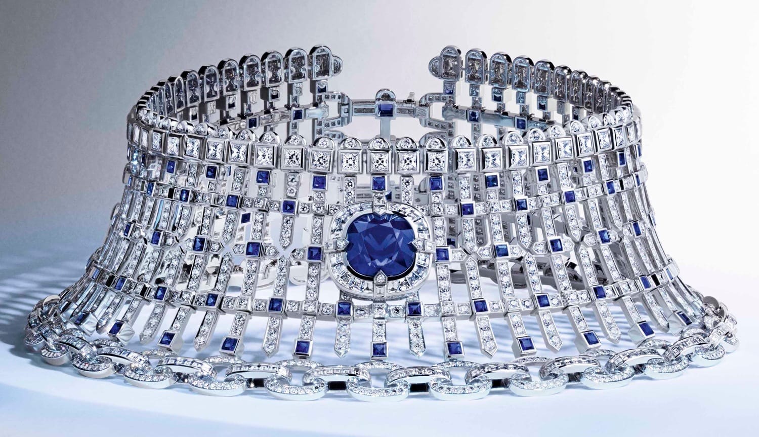 Elegant diamond and sapphire necklace with intricate design and central blue gem on a light background