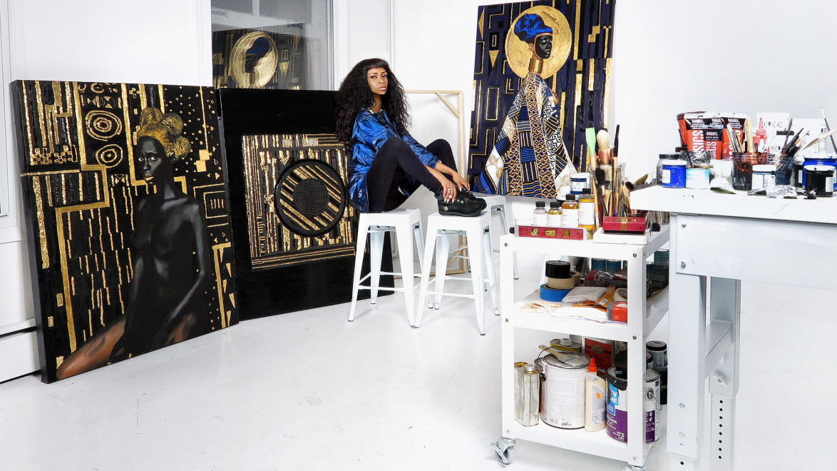 artist sitting in studio surrounded by canvas paintings and art supplies