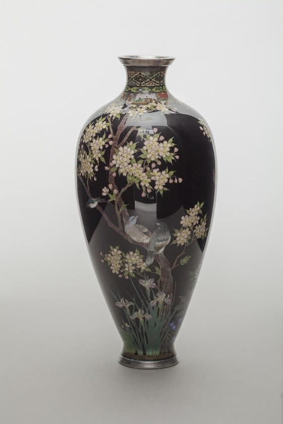 Tall black vase adorned with delicate white flowers and birds, featuring intricate detailing and a glossy finish.