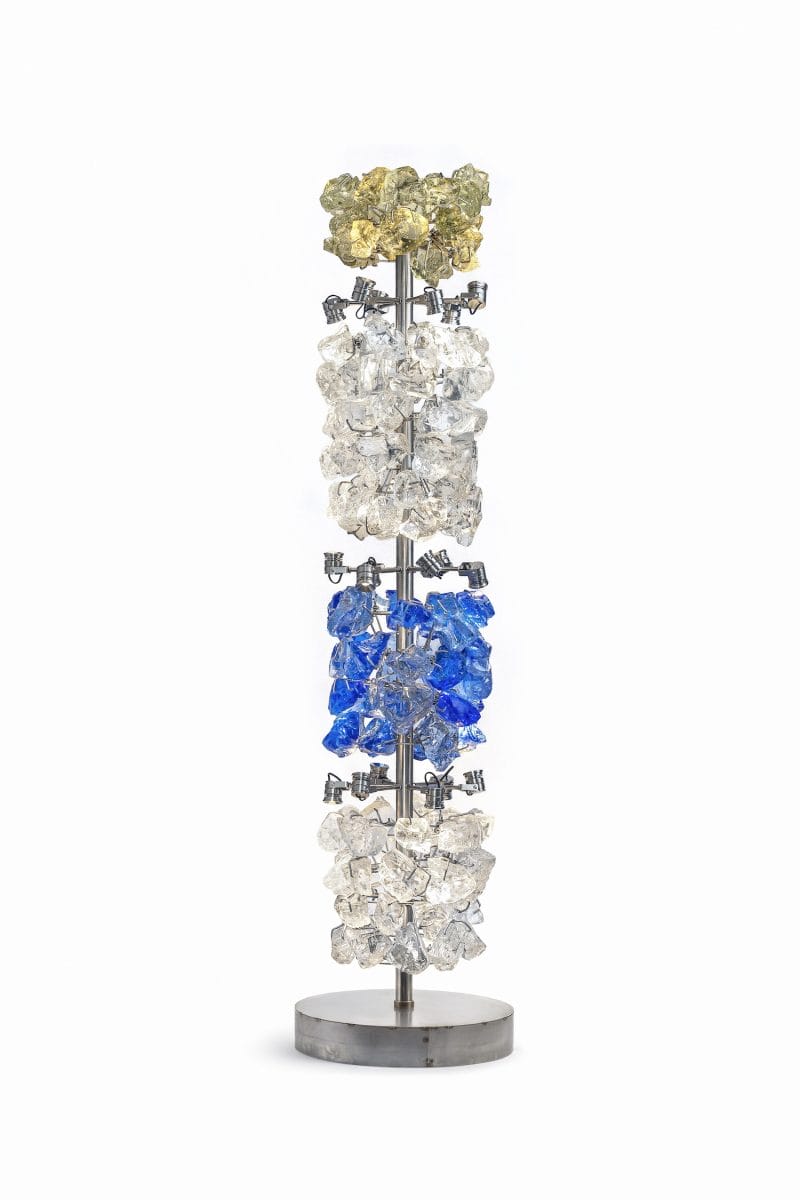 Colorful glass lamp with crystal-like clusters in yellow, clear, blue, and clear hues on a silver stand with round base.