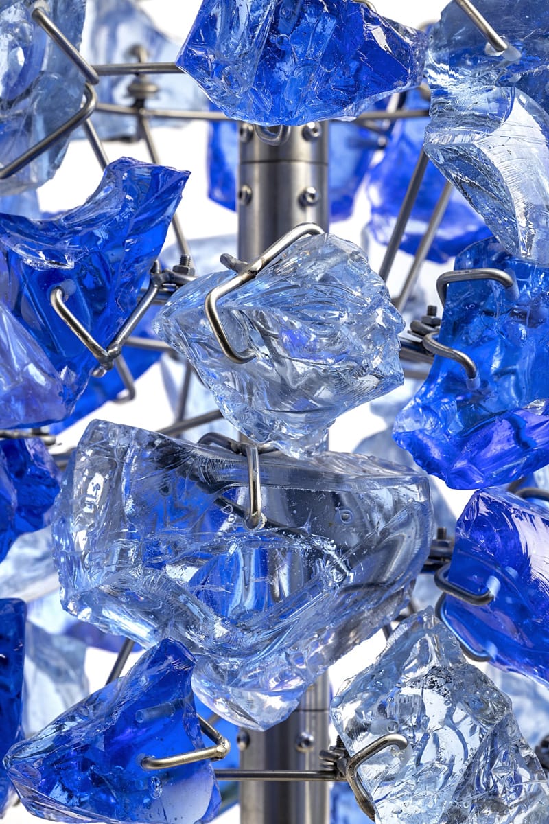 Close-up of blue and clear crystal-like stones connected by metal rods, creating an intricate and abstract design pattern.