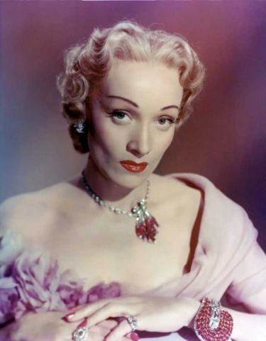 Elegant woman in vintage attire with styled blonde hair, wearing jewelry and a lavender dress, posing against a soft gradient backdrop.