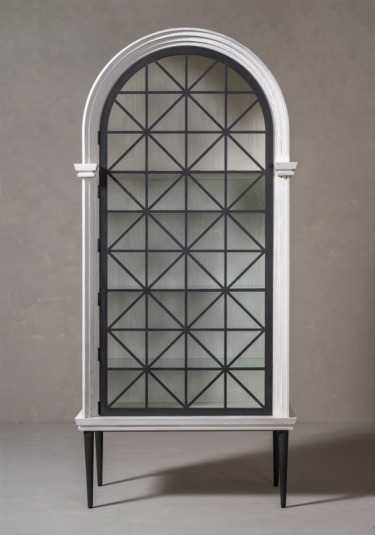 Tall arched cabinet with a geometric patterned glass door and slender black legs against a neutral background