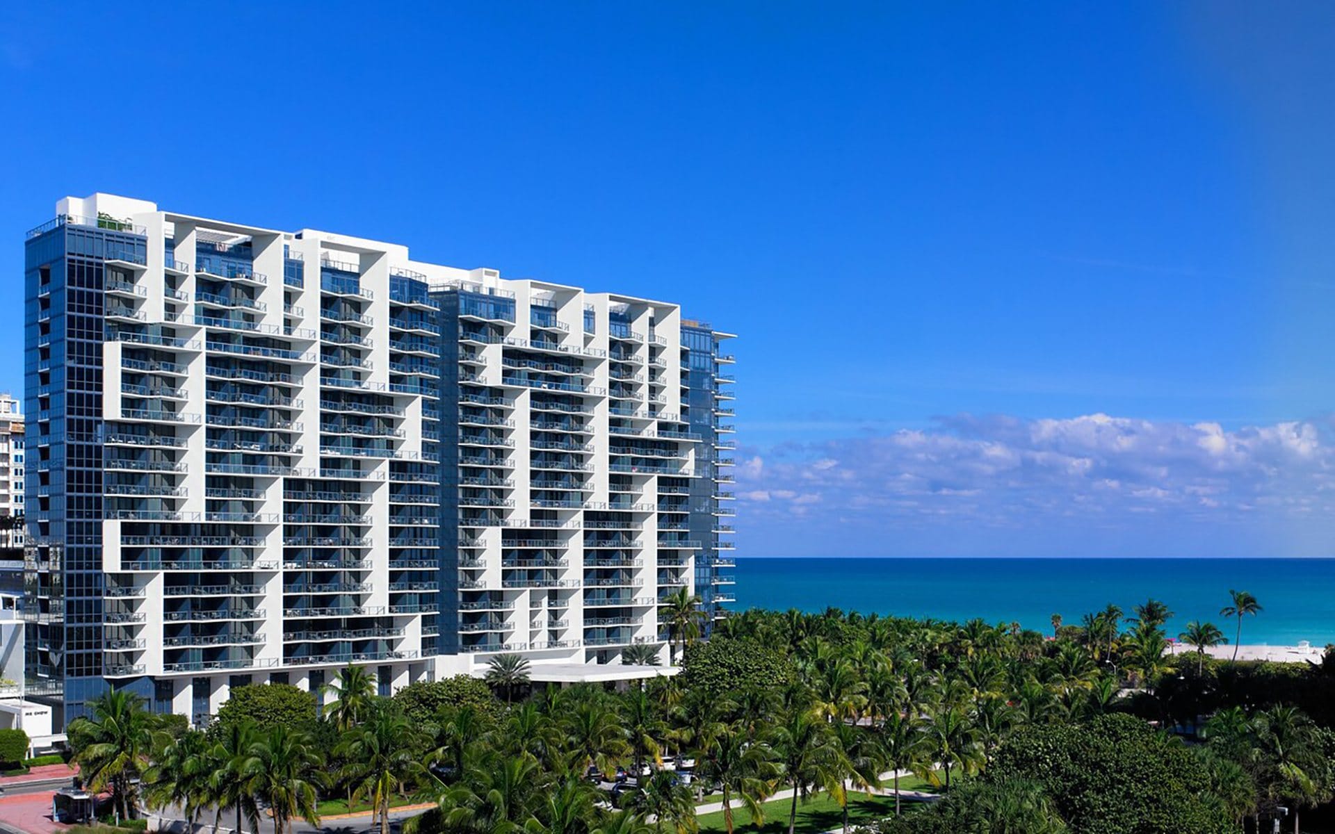 Modern beachfront condominium with blue skies and ocean in the background.