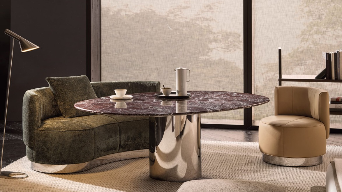 Modern living room with a marble table, green sofa, beige chair, and a floor lamp next to large windows.