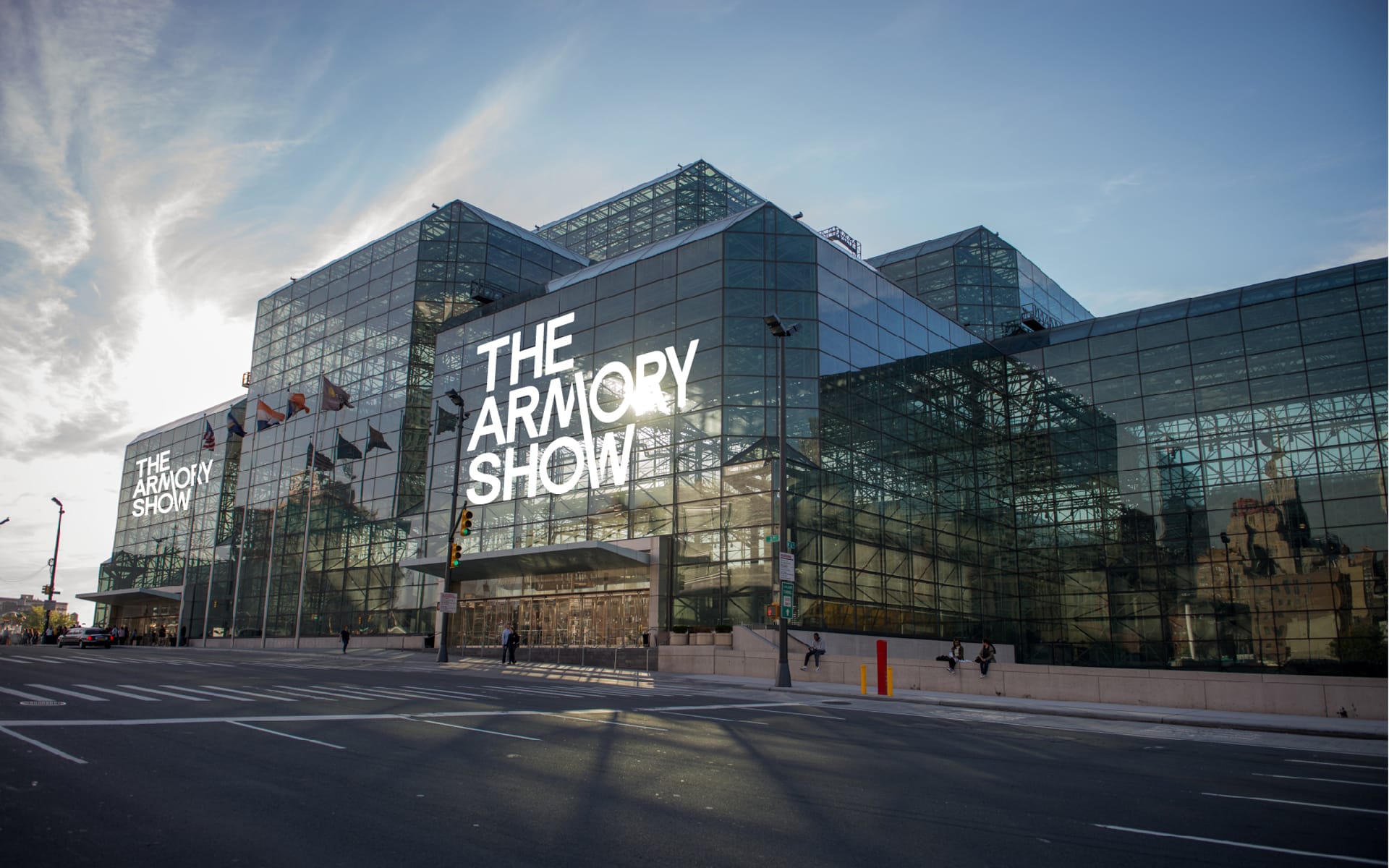 Exterior view of The Armory Show building, with large glass windows and signage against a blue sky background.