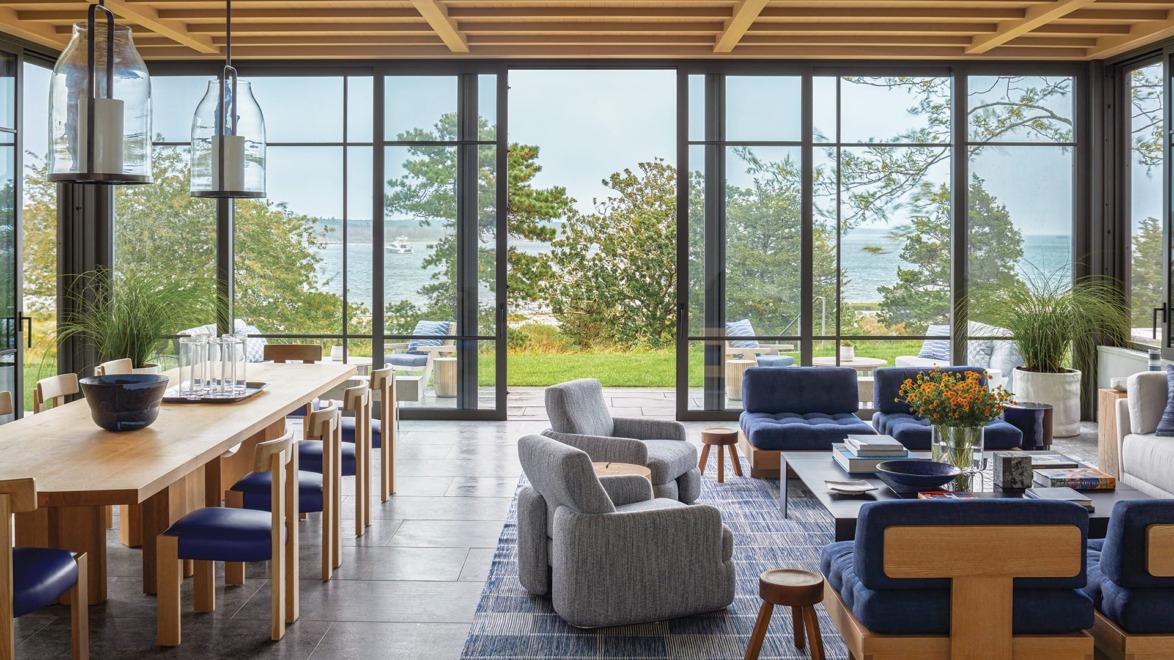 Modern open-concept living and dining area with large windows overlooking a scenic ocean view, featuring stylish furniture and decor.
